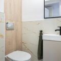Clean and stylish modern bathroom with marble tiles and a small sink.